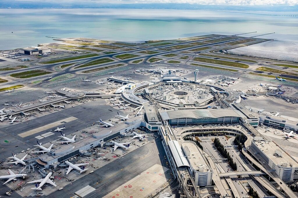 Aerial view of San Francisco International Airport Terminal One showing the circular terminal layout, aircraft gates, runways, and taxiways along San Francisco Bay.