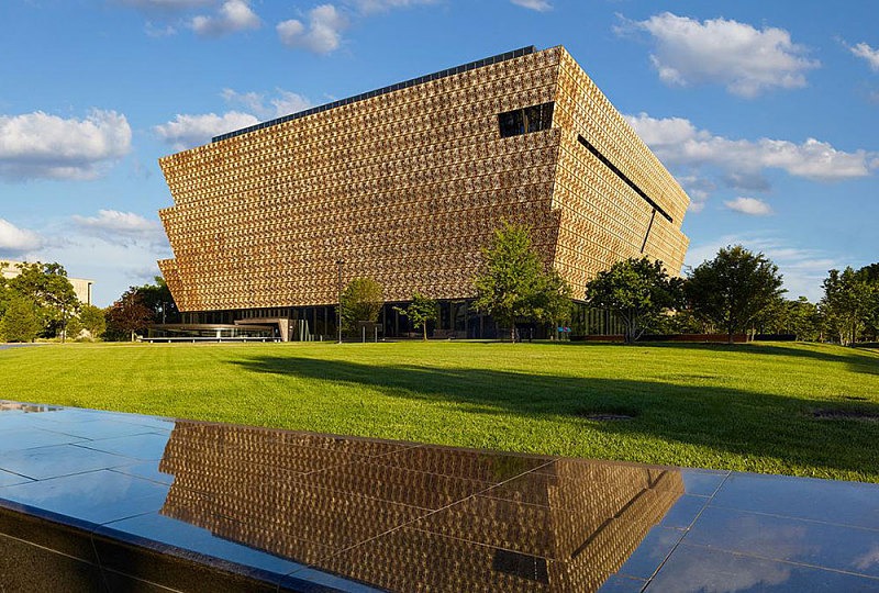 Smithsonian National Museum of African American History and Culture in Washington DC with its bronze colored lattice façade and landscaped lawn in front.